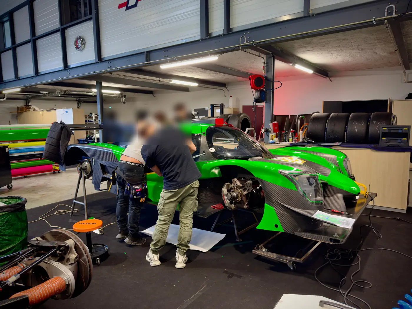 Poseurs habillant une supercar de course en covering dans l'atelier