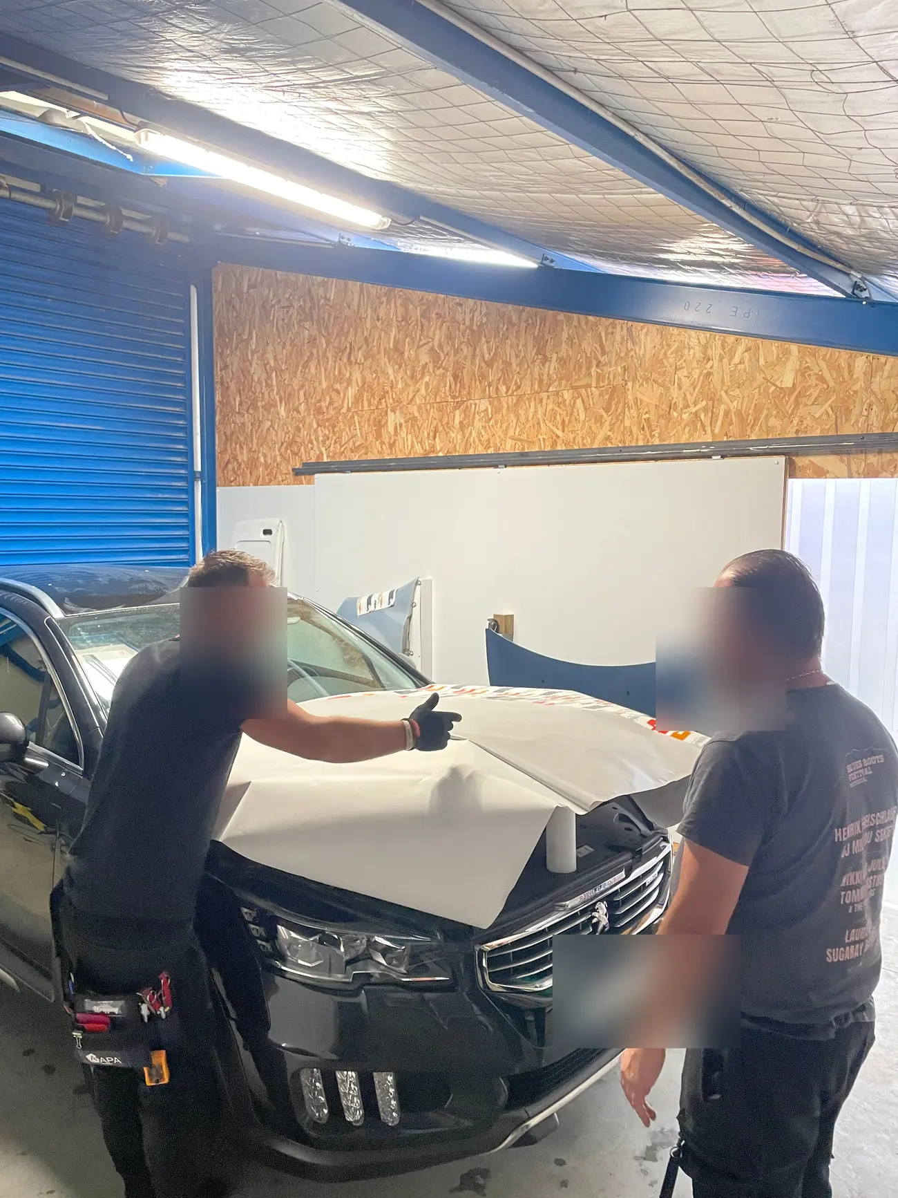 Deux poseurs professionnels appliquant un film sur le capot d'une Peugeot
